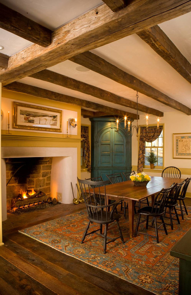 Example of a farmhouse dark wood floor enclosed dining room design in Philadelphia with beige walls and a standard fireplace
