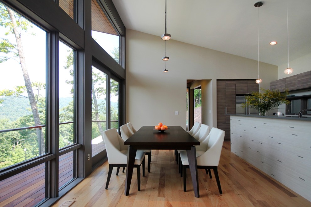 Immagine di una sala da pranzo aperta verso la cucina minimal con pareti beige e pavimento in legno massello medio