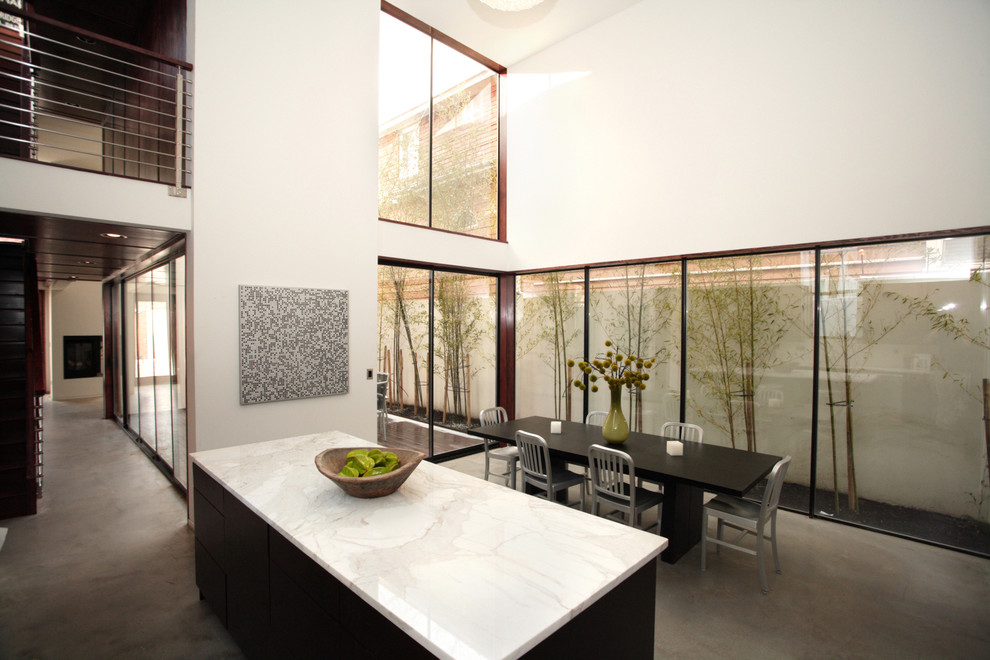 Cette image montre une salle à manger ouverte sur la cuisine minimaliste avec un mur blanc.