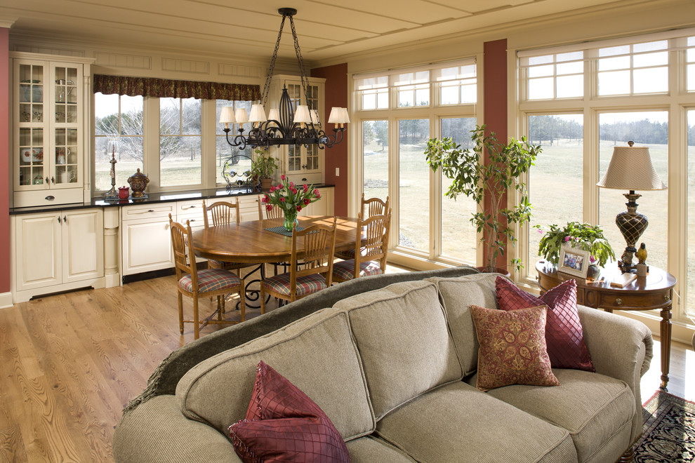 Immagine di una grande sala da pranzo aperta verso la cucina country con pavimento in legno massello medio e pareti rosse