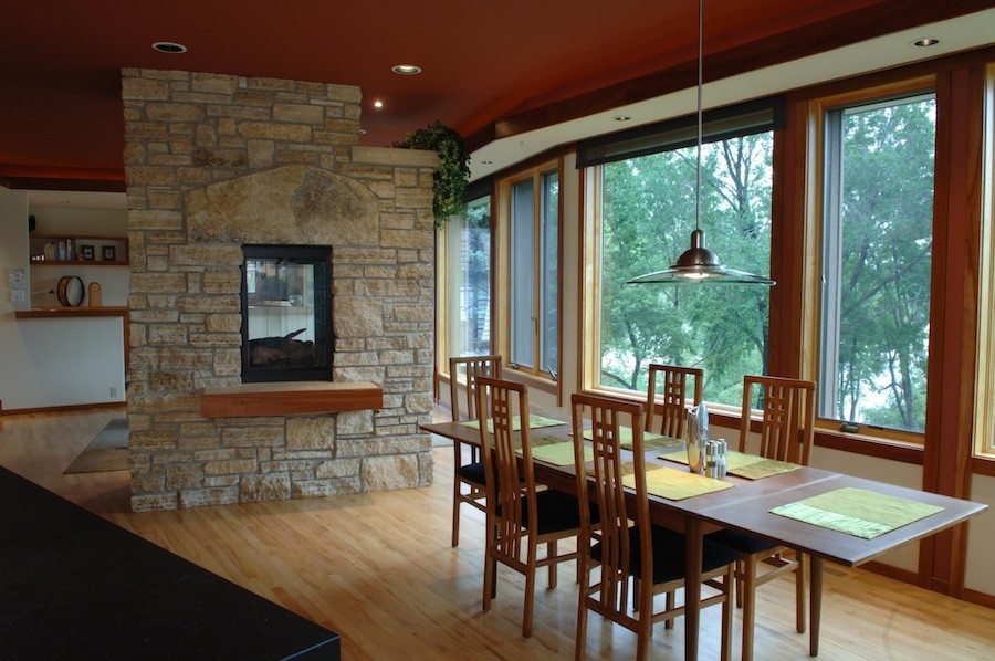 Foto de comedor de cocina clásico de tamaño medio con paredes blancas, suelo de madera clara, chimenea de doble cara y marco de chimenea de piedra