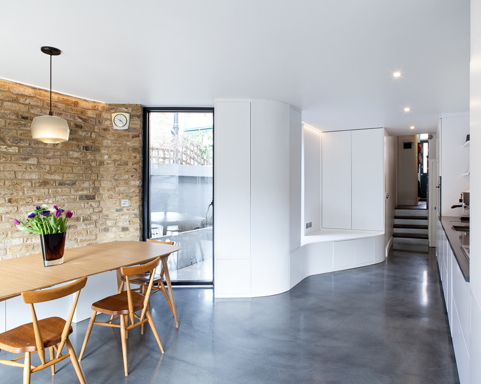 Idee per una sala da pranzo aperta verso il soggiorno minimal di medie dimensioni con pareti bianche, pavimento in cemento, nessun camino e pavimento grigio