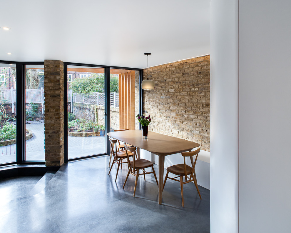 Cette photo montre une salle à manger ouverte sur le salon tendance de taille moyenne avec un mur blanc, sol en béton ciré, aucune cheminée et un sol gris.