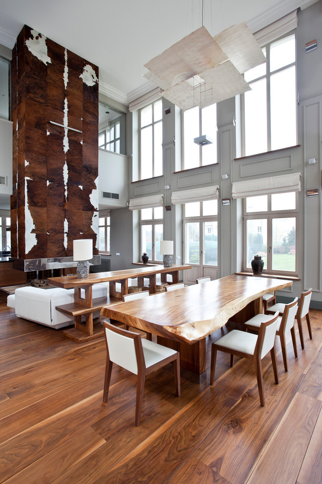 Idee per una sala da pranzo contemporanea con pareti grigie, pavimento in legno massello medio e camino bifacciale