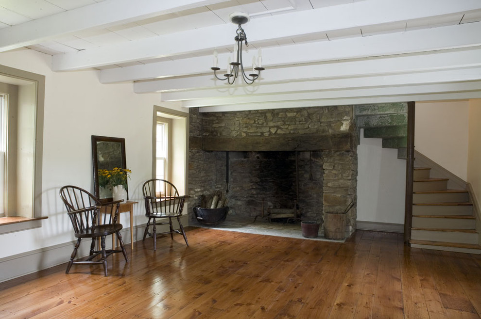 Ejemplo de comedor de estilo de casa de campo cerrado con paredes blancas, suelo de madera en tonos medios, todas las chimeneas y marco de chimenea de piedra