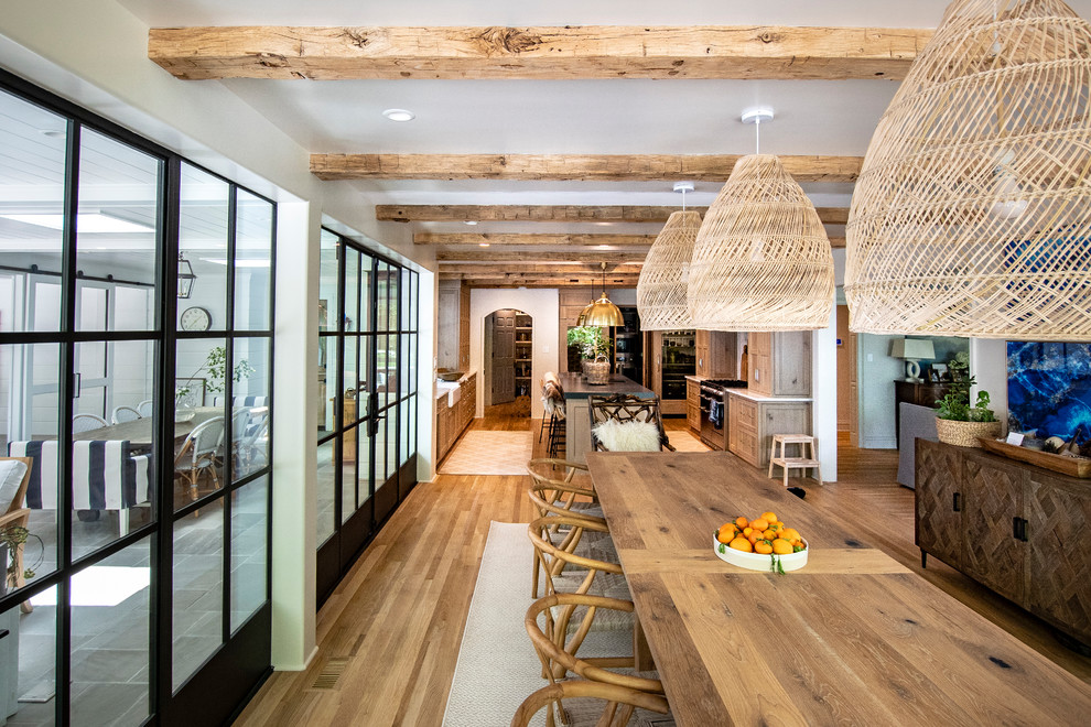 Große Country Wohnküche mit weißer Wandfarbe, hellem Holzboden und braunem Boden in Sonstige