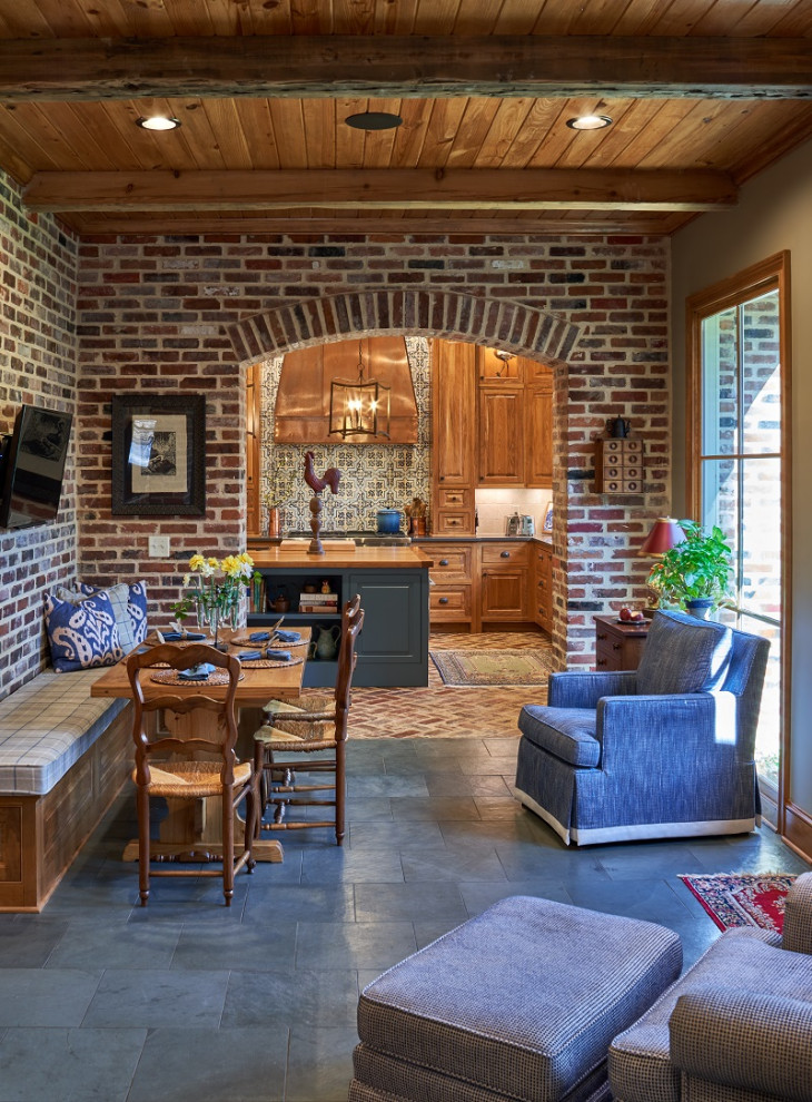 Idée de décoration pour une grande salle à manger ouverte sur la cuisine champêtre avec un mur gris, un sol gris, un plafond en bois et un mur en parement de brique.