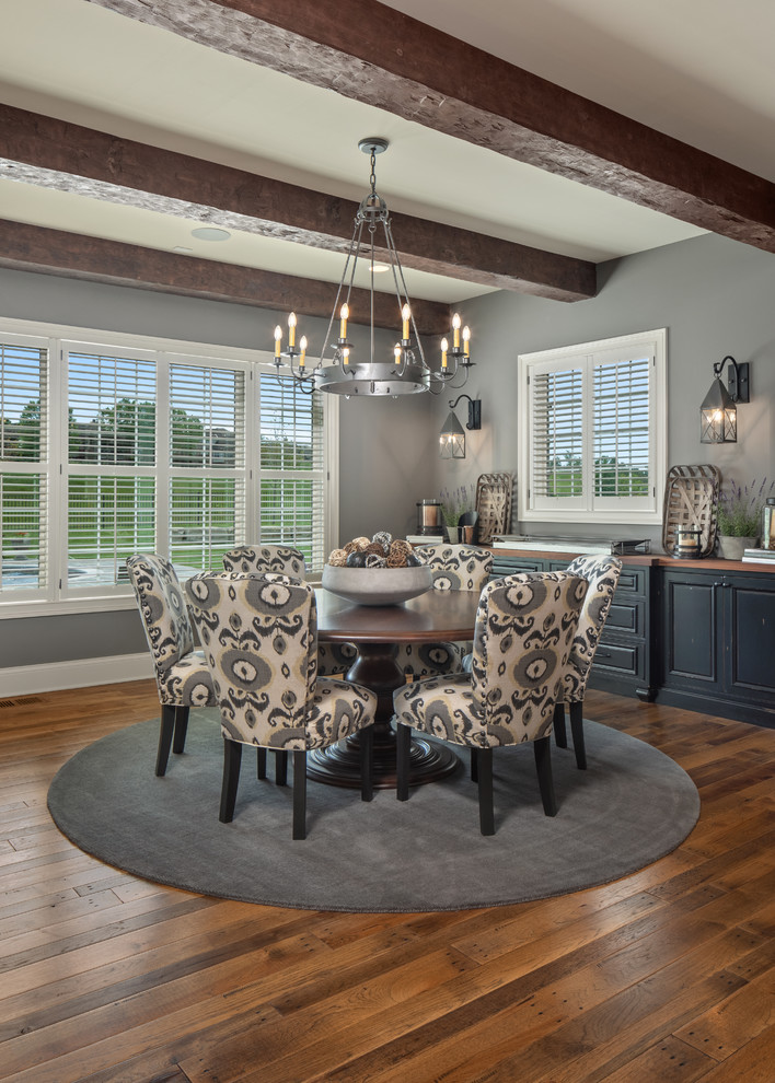 Cette image montre une salle à manger ouverte sur la cuisine traditionnelle de taille moyenne avec un mur gris, parquet foncé et un sol marron.