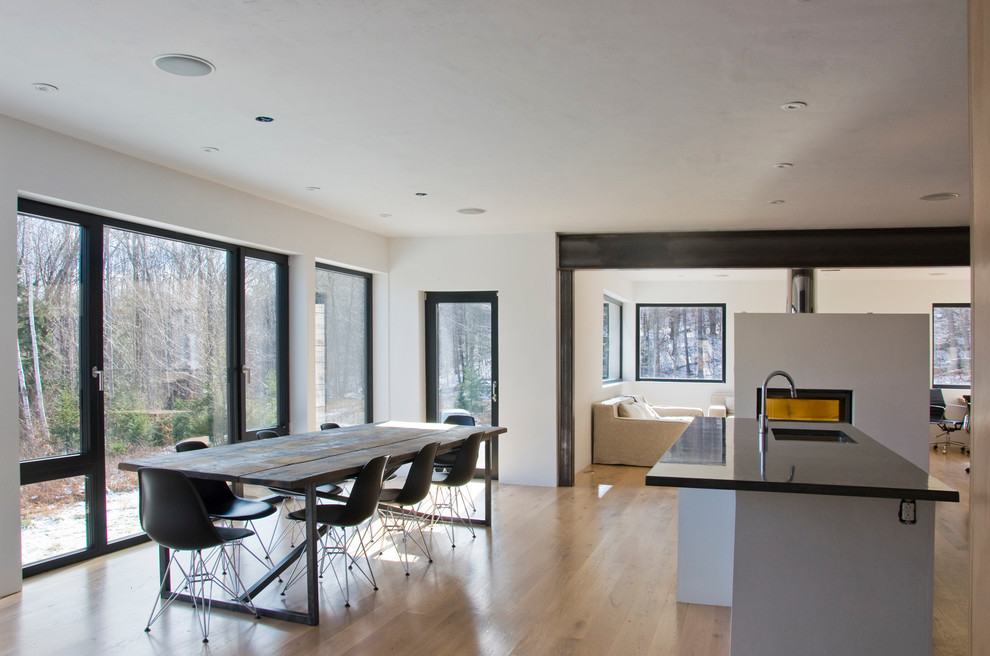 Aménagement d'une salle à manger ouverte sur le salon contemporaine avec un mur blanc et un sol en bois brun.