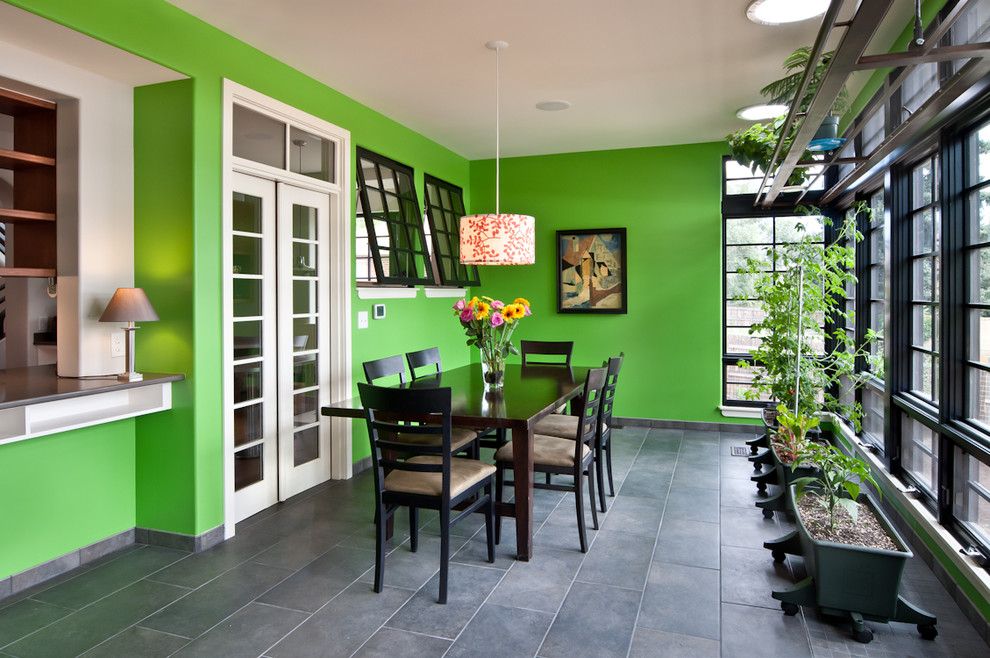 Cette photo montre une grande salle à manger tendance fermée avec un mur vert, un sol en carrelage de porcelaine, un sol gris et éclairage.
