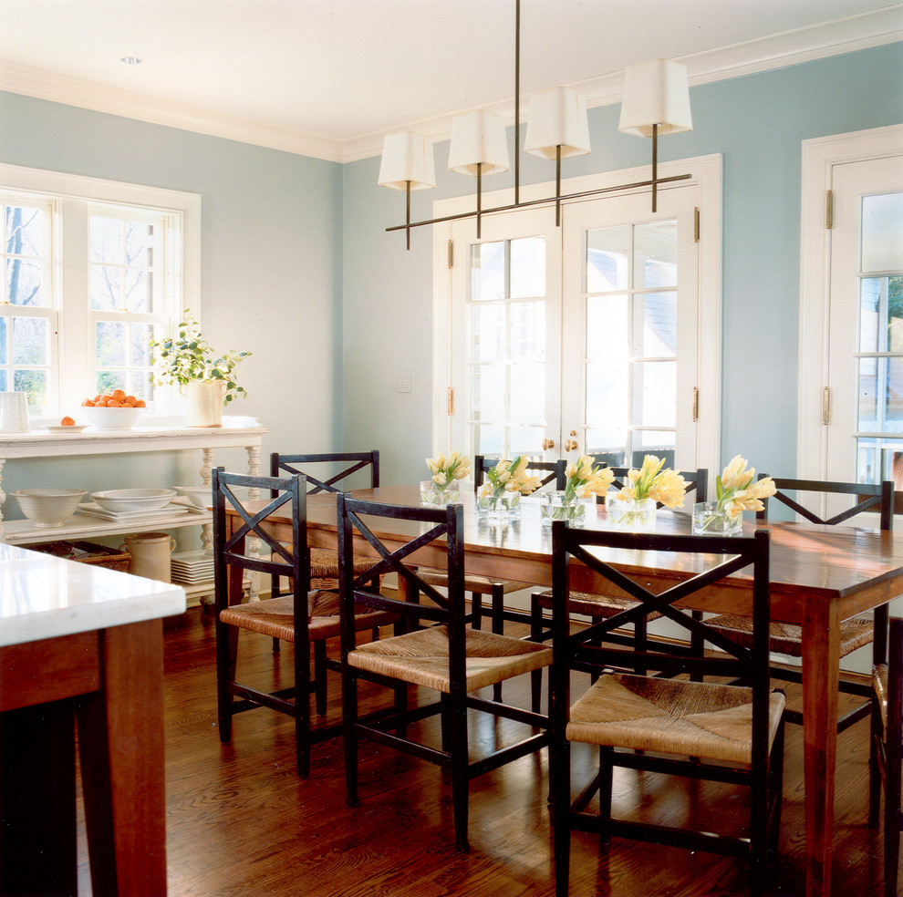 Aménagement d'une salle à manger ouverte sur la cuisine campagne avec un mur bleu et un sol en bois brun.