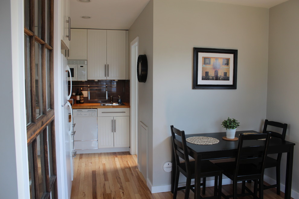 Idée de décoration pour une petite salle à manger ouverte sur la cuisine minimaliste avec un mur gris et parquet clair.