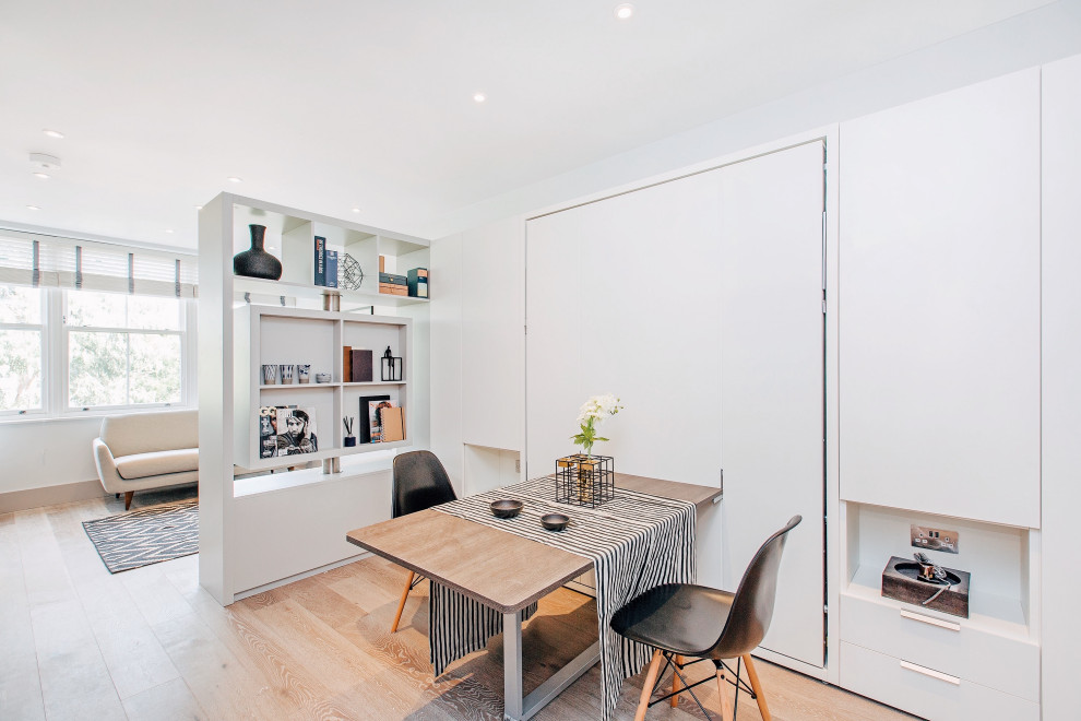 Cette image montre une petite salle à manger ouverte sur le salon minimaliste avec parquet clair, un sol beige et un mur gris.