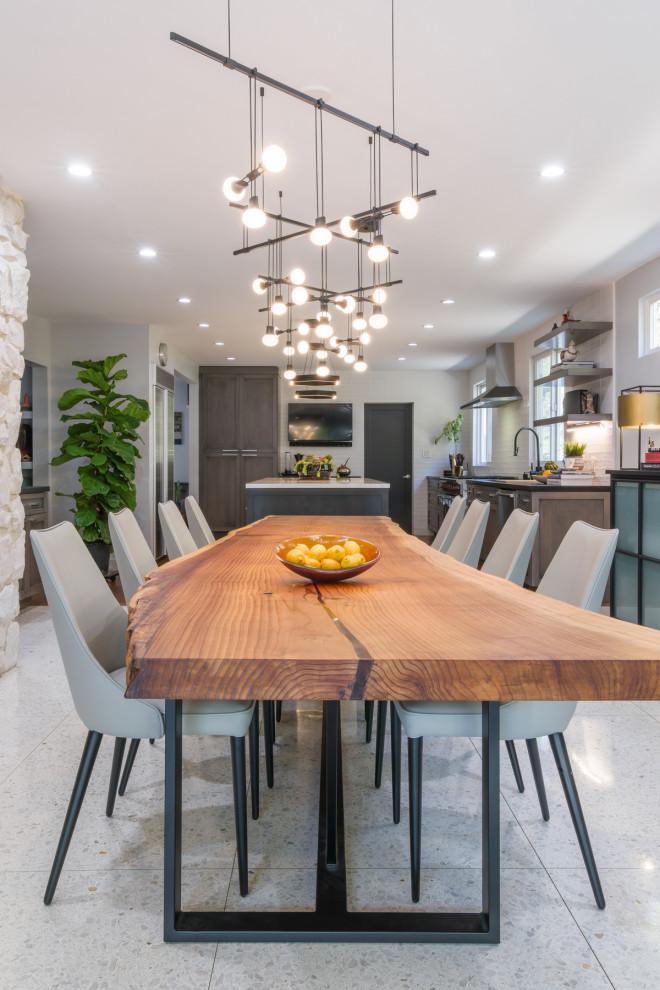 Example of a large trendy porcelain tile and white floor kitchen/dining room combo design in Los Angeles with a hanging fireplace, a stone fireplace and gray walls