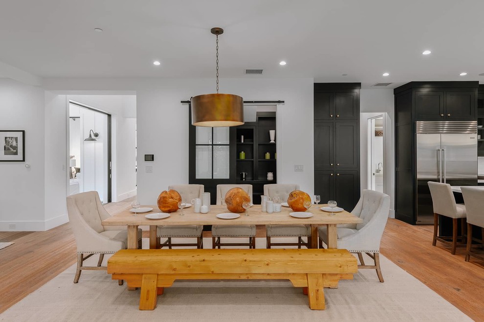 Cette image montre une salle à manger ouverte sur le salon rustique de taille moyenne avec un mur blanc, un sol en bois brun et un sol marron.
