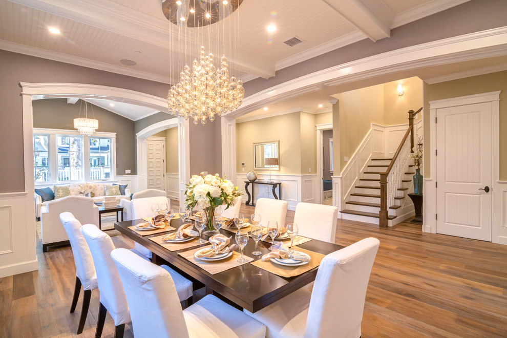 This is an example of a medium sized classic enclosed dining room in Los Angeles with grey walls, laminate floors, a standard fireplace, a wooden fireplace surround and brown floors.