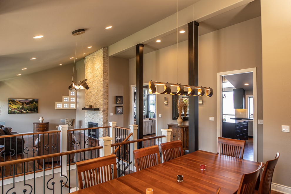 Idée de décoration pour une très grande salle à manger ouverte sur la cuisine design avec un mur beige, un sol en bois brun, une cheminée standard, un manteau de cheminée en pierre et un sol marron.