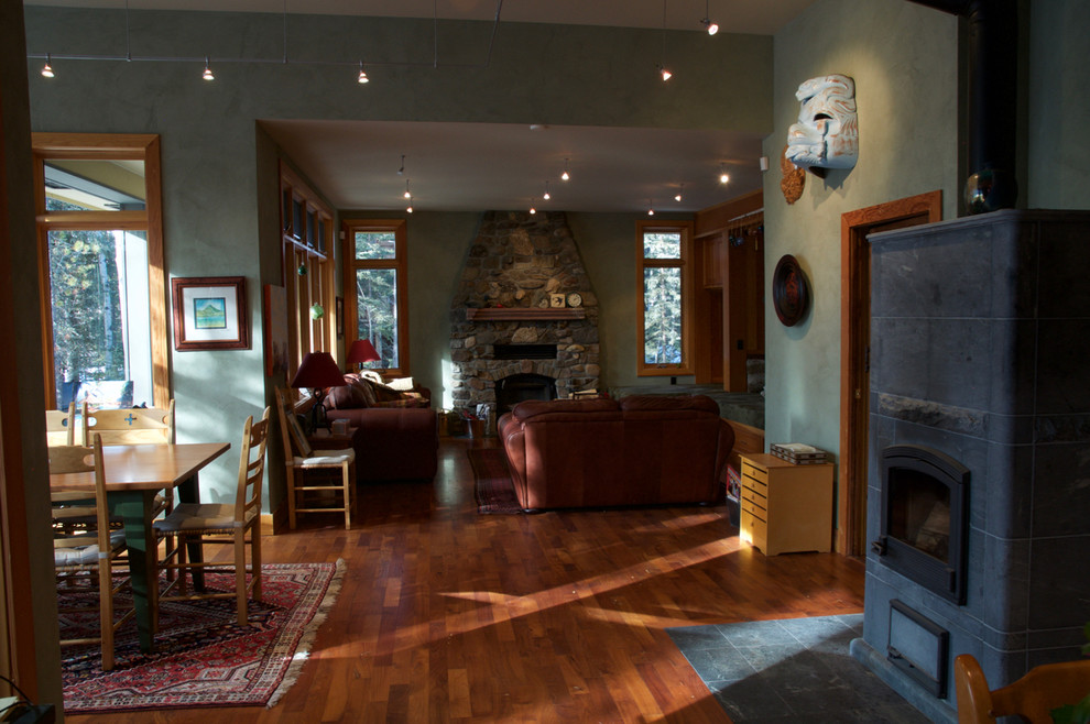 Réalisation d'une salle à manger ouverte sur le salon design de taille moyenne avec un mur vert, parquet foncé, une cheminée standard et un manteau de cheminée en pierre.