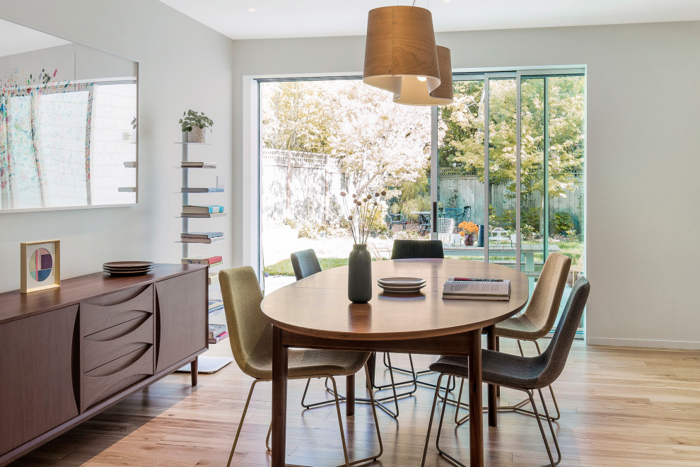 Design ideas for a retro dining room in San Francisco with white walls, light hardwood flooring and brown floors.