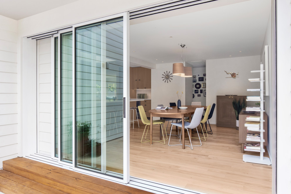 Midcentury dining room in San Francisco with white walls, light hardwood flooring and brown floors.