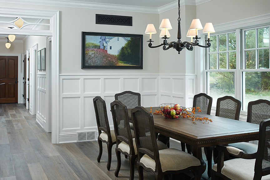 Cette image montre une salle à manger ouverte sur la cuisine traditionnelle avec boiseries, un mur gris, un sol en vinyl et un sol multicolore.
