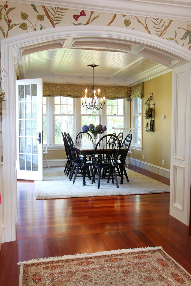 Foto di una grande sala da pranzo aperta verso la cucina chic con pareti gialle, pavimento in legno massello medio, nessun camino e pavimento marrone