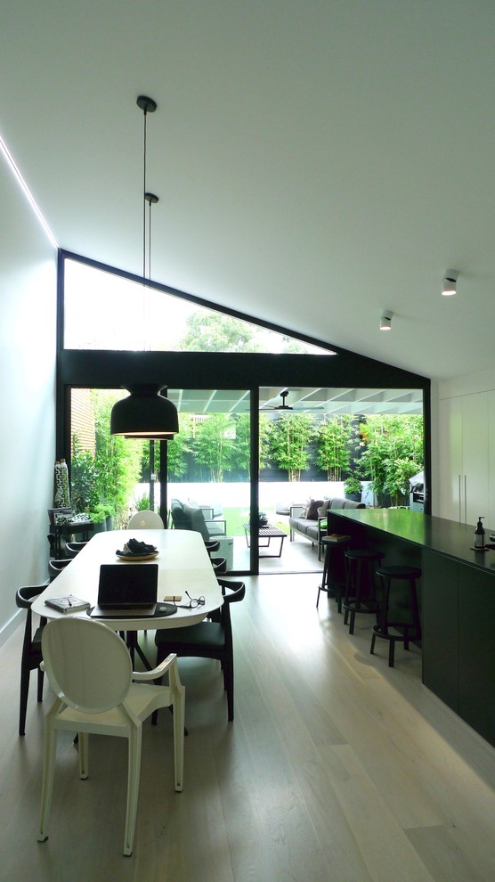 Immagine di una sala da pranzo aperta verso il soggiorno minimalista di medie dimensioni con pareti bianche, pavimento in legno verniciato e pavimento bianco