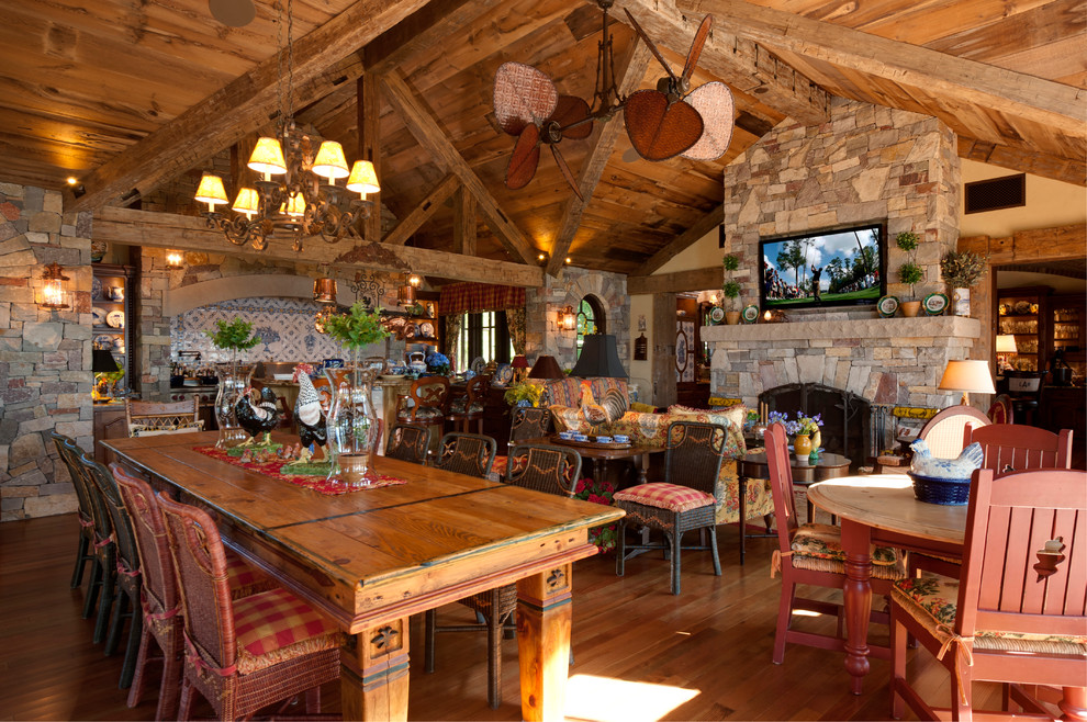 Esempio di una sala da pranzo aperta verso la cucina tradizionale con parquet scuro, camino classico e cornice del camino in pietra