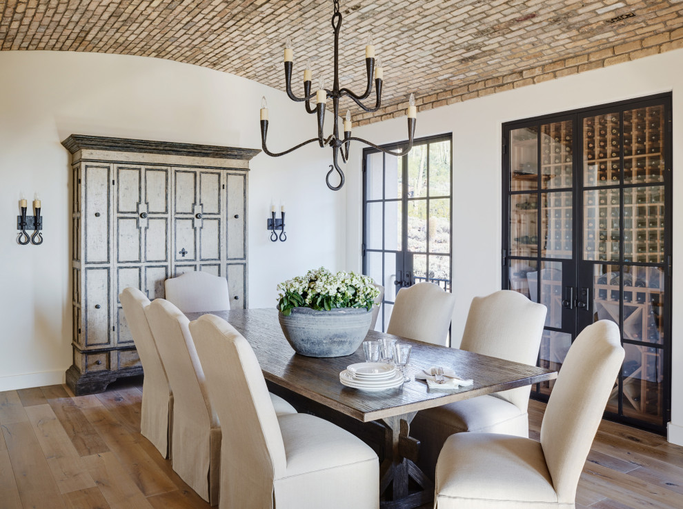 Foto di una sala da pranzo mediterranea chiusa con pareti bianche, pavimento in legno massello medio, nessun camino, pavimento marrone e soffitto a volta