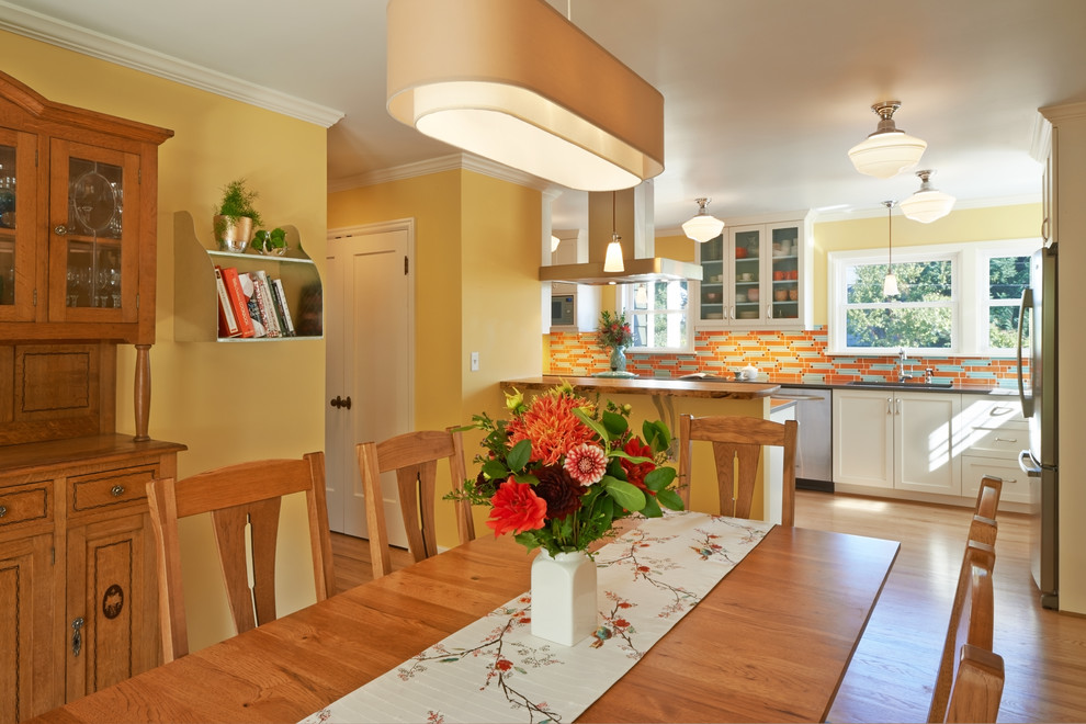 Exemple d'une salle à manger ouverte sur la cuisine éclectique de taille moyenne avec un mur jaune, un sol en bois brun et aucune cheminée.