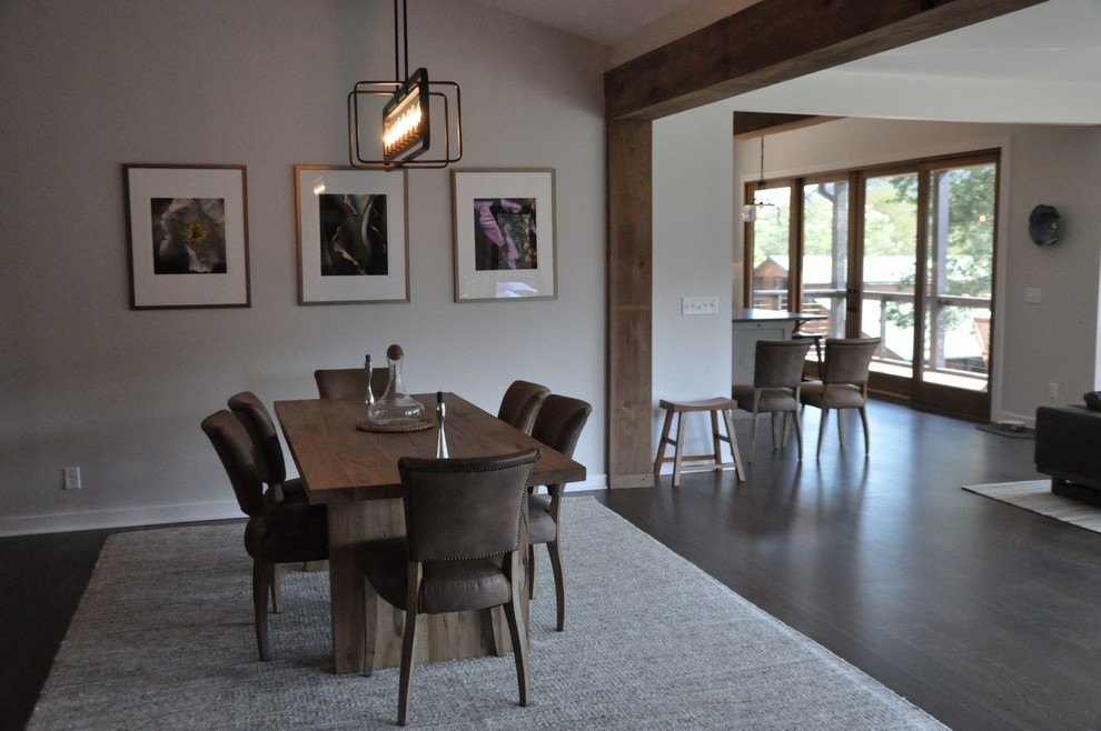 Exemple d'une salle à manger ouverte sur le salon nature de taille moyenne avec un mur blanc, parquet foncé, une cheminée standard, un manteau de cheminée en brique et un sol gris.