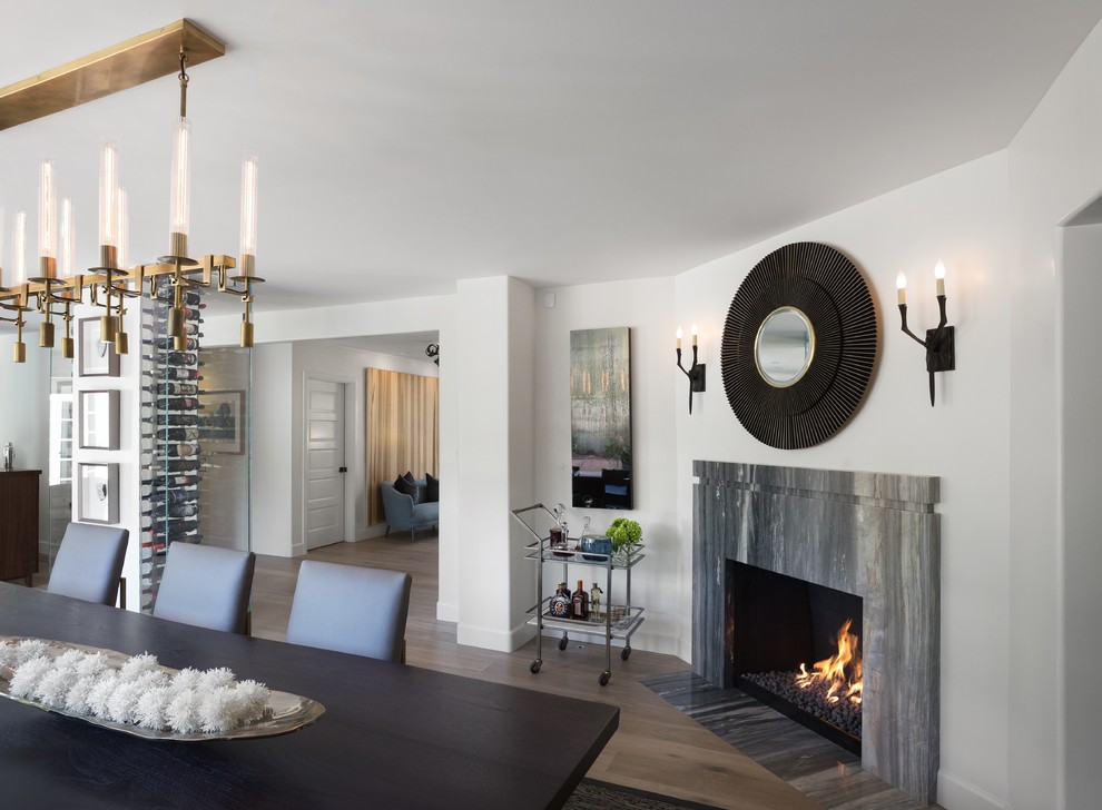 Inspiration for a large transitional medium tone wood floor and brown floor dining room remodel in Los Angeles with white walls, a standard fireplace and a stone fireplace