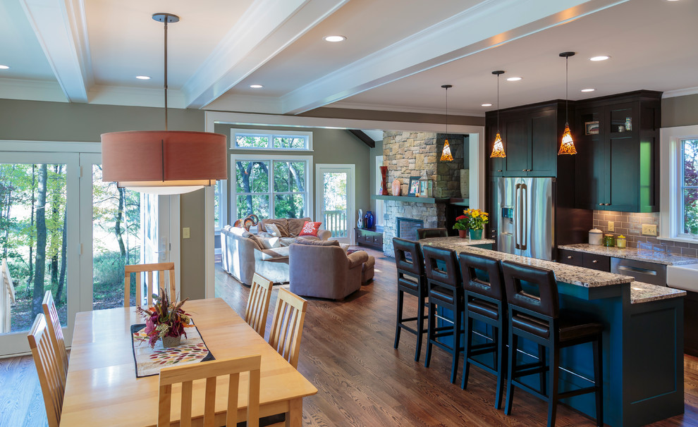 Aménagement d'une salle à manger ouverte sur le salon classique de taille moyenne avec un mur vert, un sol en bois brun, une cheminée standard et un manteau de cheminée en pierre.