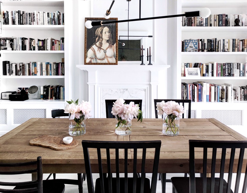 This is an example of a scandi dining room in New York with white walls, a standard fireplace and a stone fireplace surround.