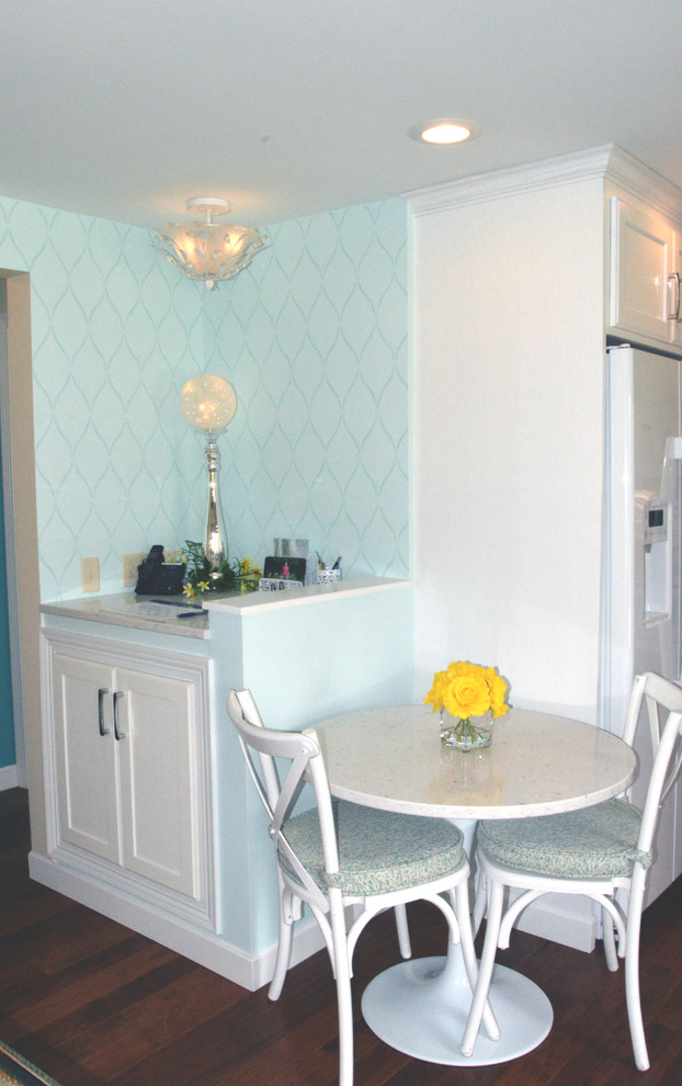 Cette image montre une petite salle à manger ouverte sur la cuisine marine avec un mur bleu, parquet foncé et un sol marron.