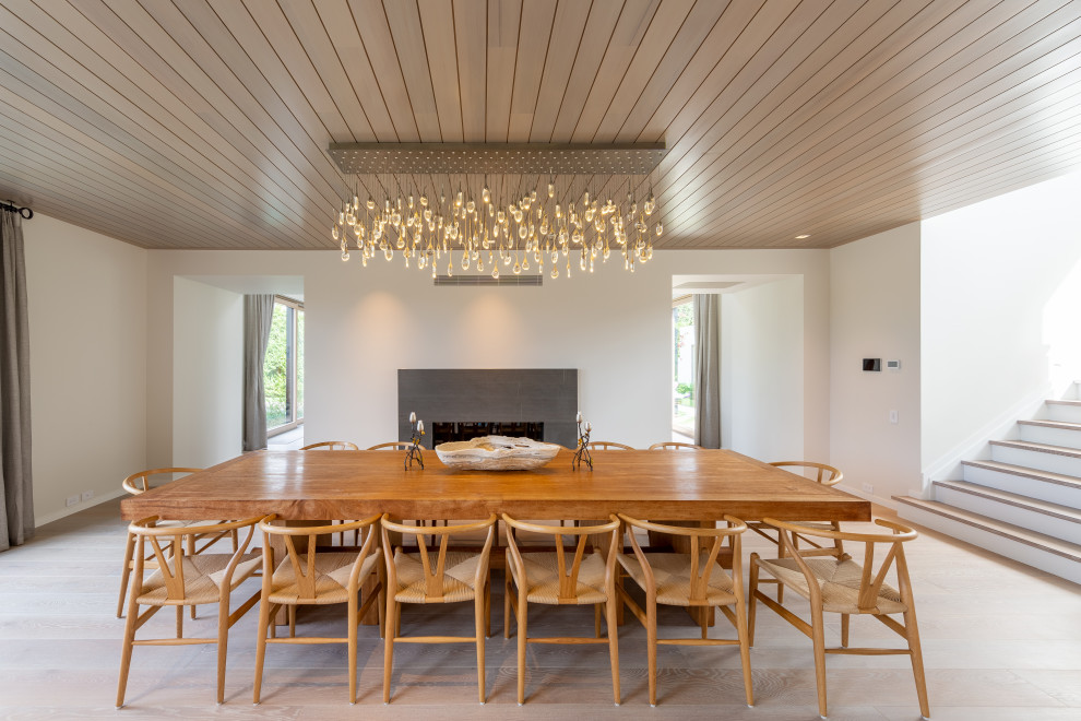 Idées déco pour une salle à manger moderne avec un mur blanc, parquet clair, une cheminée standard et un sol beige.