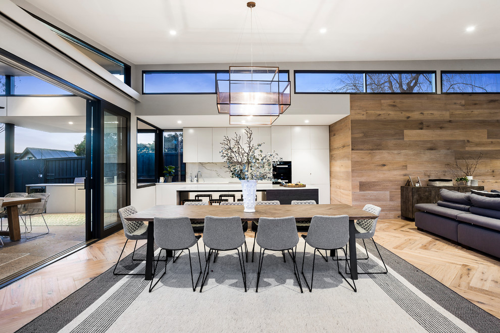 Foto di una sala da pranzo aperta verso la cucina moderna di medie dimensioni con pareti marroni, parquet chiaro e pavimento marrone