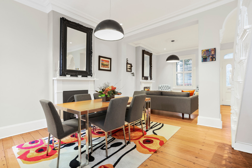 Réalisation d'une grande salle à manger ouverte sur le salon design avec un mur gris, un sol en bois brun, une cheminée standard, un manteau de cheminée en métal et un sol marron.