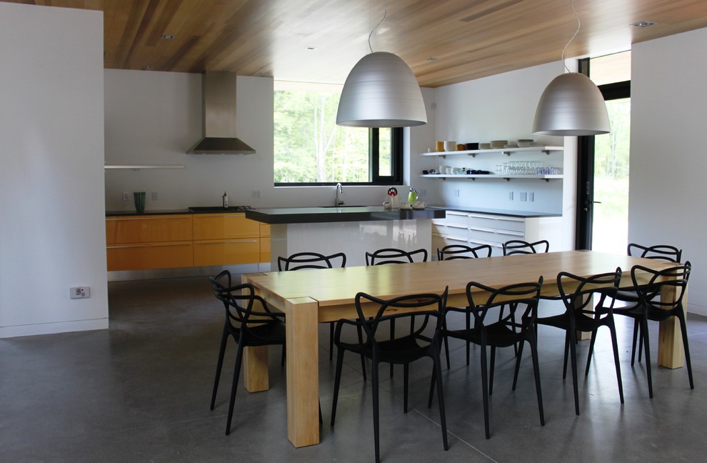 Réalisation d'une grande salle à manger ouverte sur la cuisine minimaliste avec sol en béton ciré et un mur blanc.
