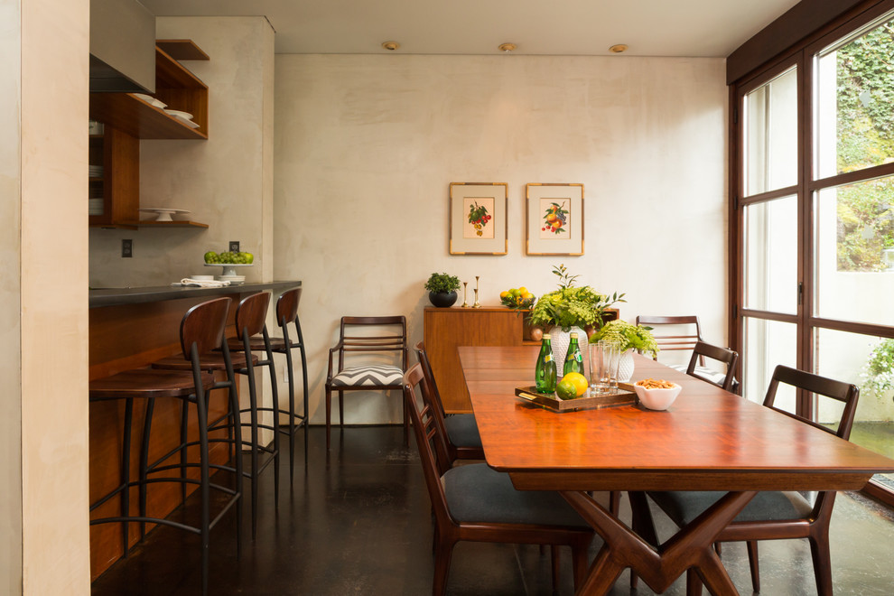 Immagine di una sala da pranzo aperta verso la cucina minimal di medie dimensioni con pavimento in cemento, pareti beige e nessun camino