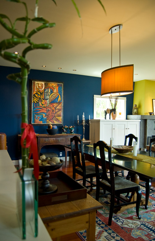 Cette image montre une salle à manger traditionnelle avec un mur bleu, un sol en bois brun, une cheminée standard, un manteau de cheminée en béton et un sol marron.
