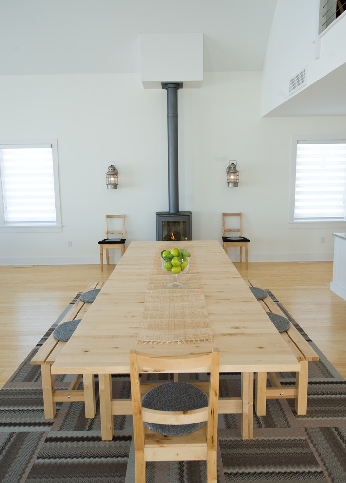 Exemple d'une salle à manger scandinave avec un mur blanc, un sol en bois brun et un poêle à bois.