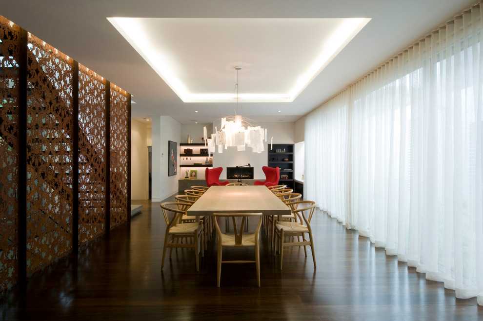 Photo of an expansive modern open plan dining room in Melbourne with white walls, dark hardwood flooring and a ribbon fireplace.