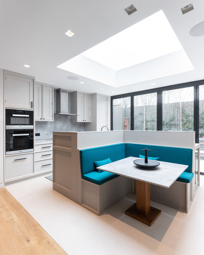 Contemporary kitchen/dining room in London with white walls and white floors.