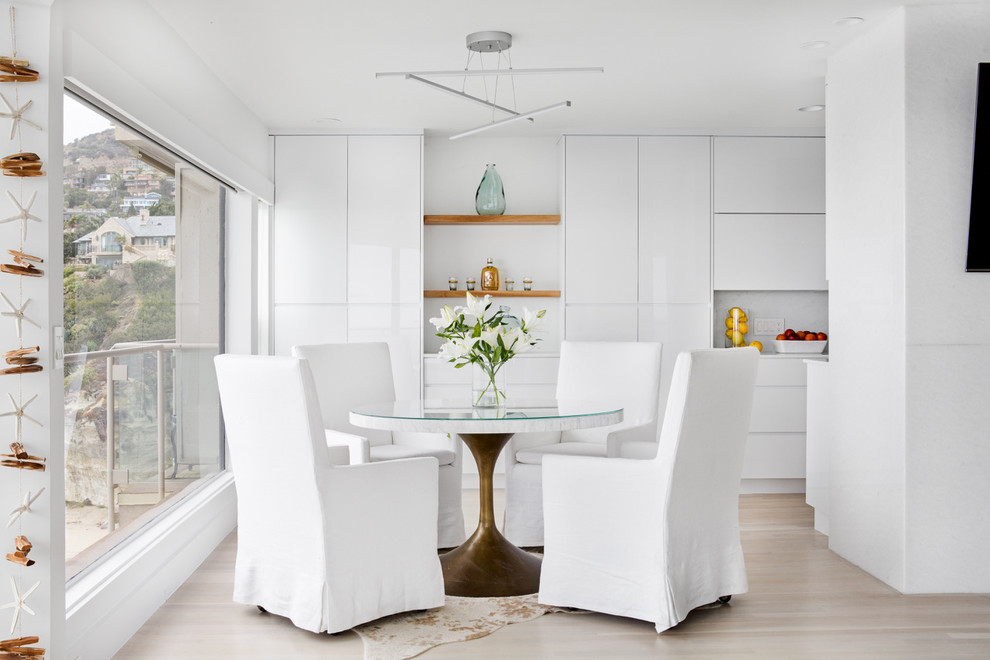 На фото: кухня-столовая в современном стиле с белыми стенами и светлым паркетным полом с