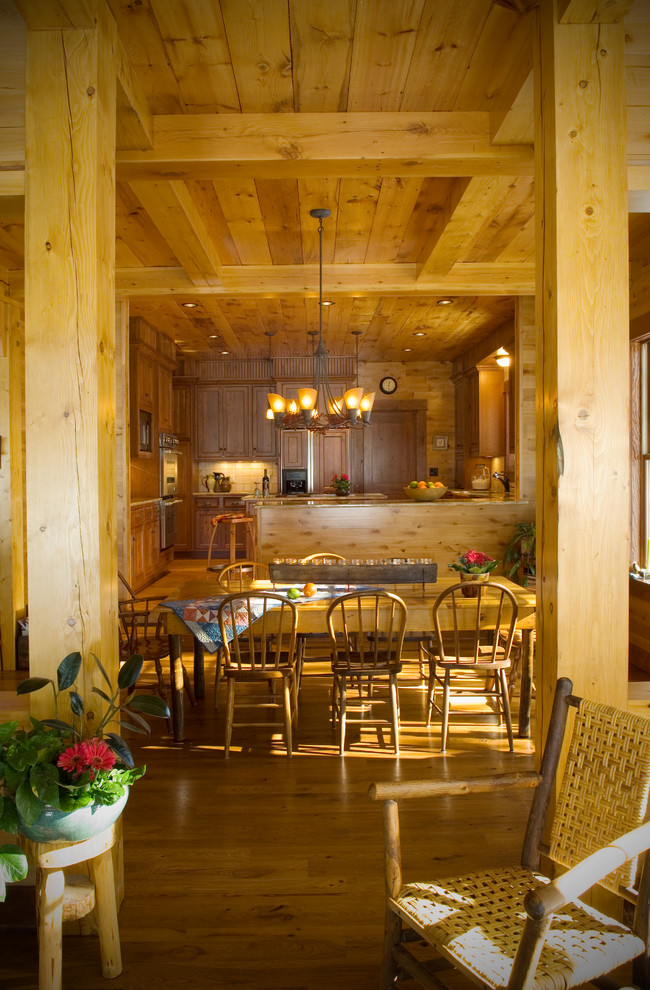 Idée de décoration pour une salle à manger ouverte sur la cuisine chalet avec un mur marron et parquet clair.