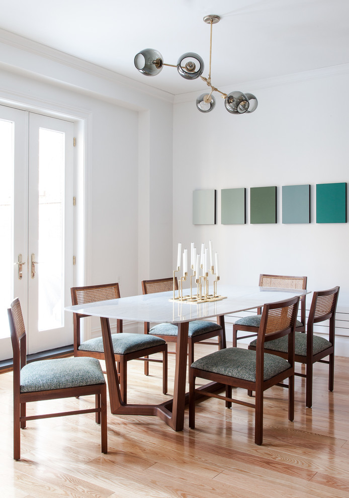 Cette image montre une grande salle à manger ouverte sur la cuisine traditionnelle avec un mur blanc et un sol en bois brun.