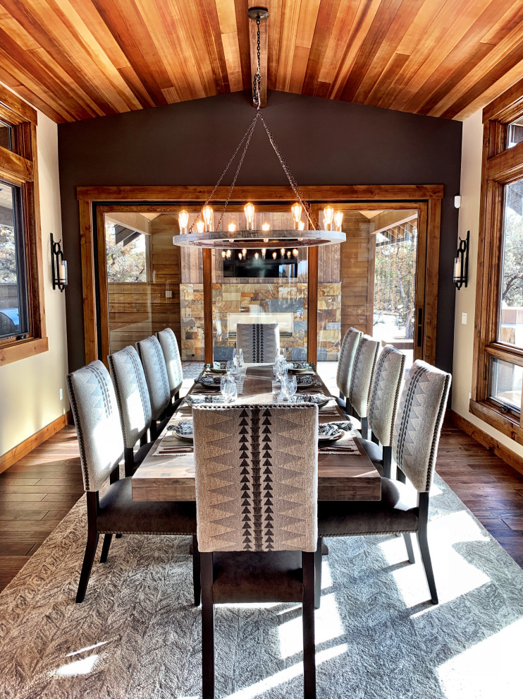 Immagine di una grande sala da pranzo aperta verso il soggiorno stile rurale con pareti grigie, parquet scuro e pavimento marrone