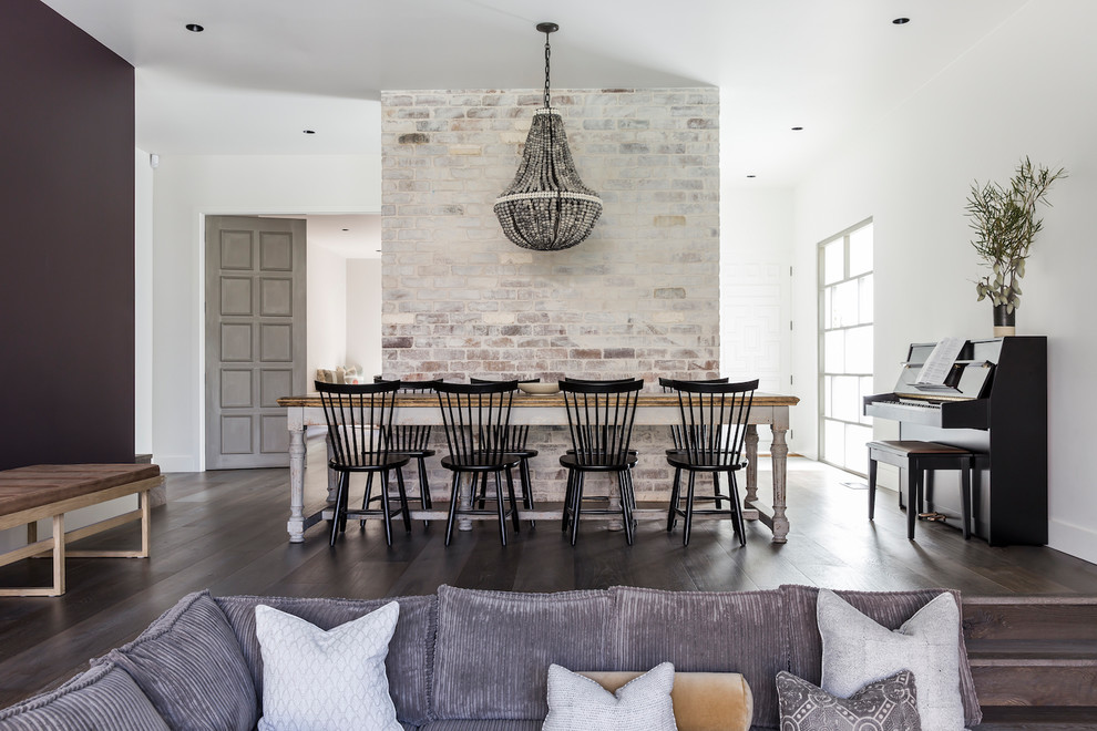 Exemple d'une grande salle à manger ouverte sur le salon tendance avec un mur blanc, un sol en bois brun, une cheminée standard, un manteau de cheminée en pierre et un sol beige.