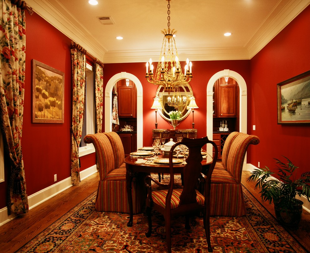 На фото: кухня-столовая в классическом стиле с красными стенами и паркетным полом среднего тона